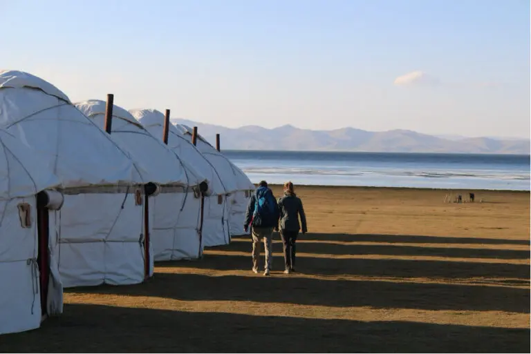 yurt camp along the lake with two people walking