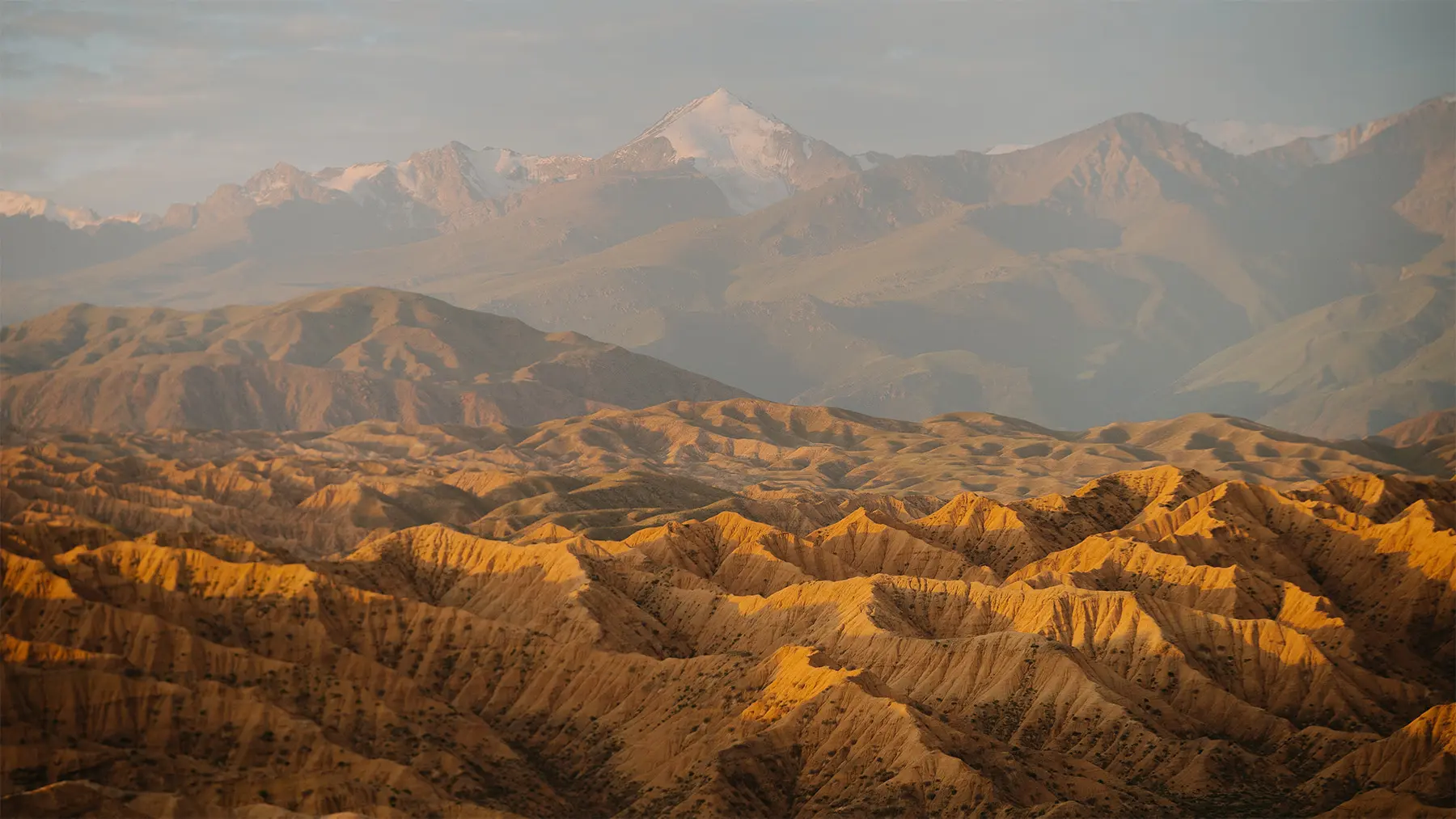 Panorama van een ruig berglandschap in Kirgizië met goudkleurige heuvels.