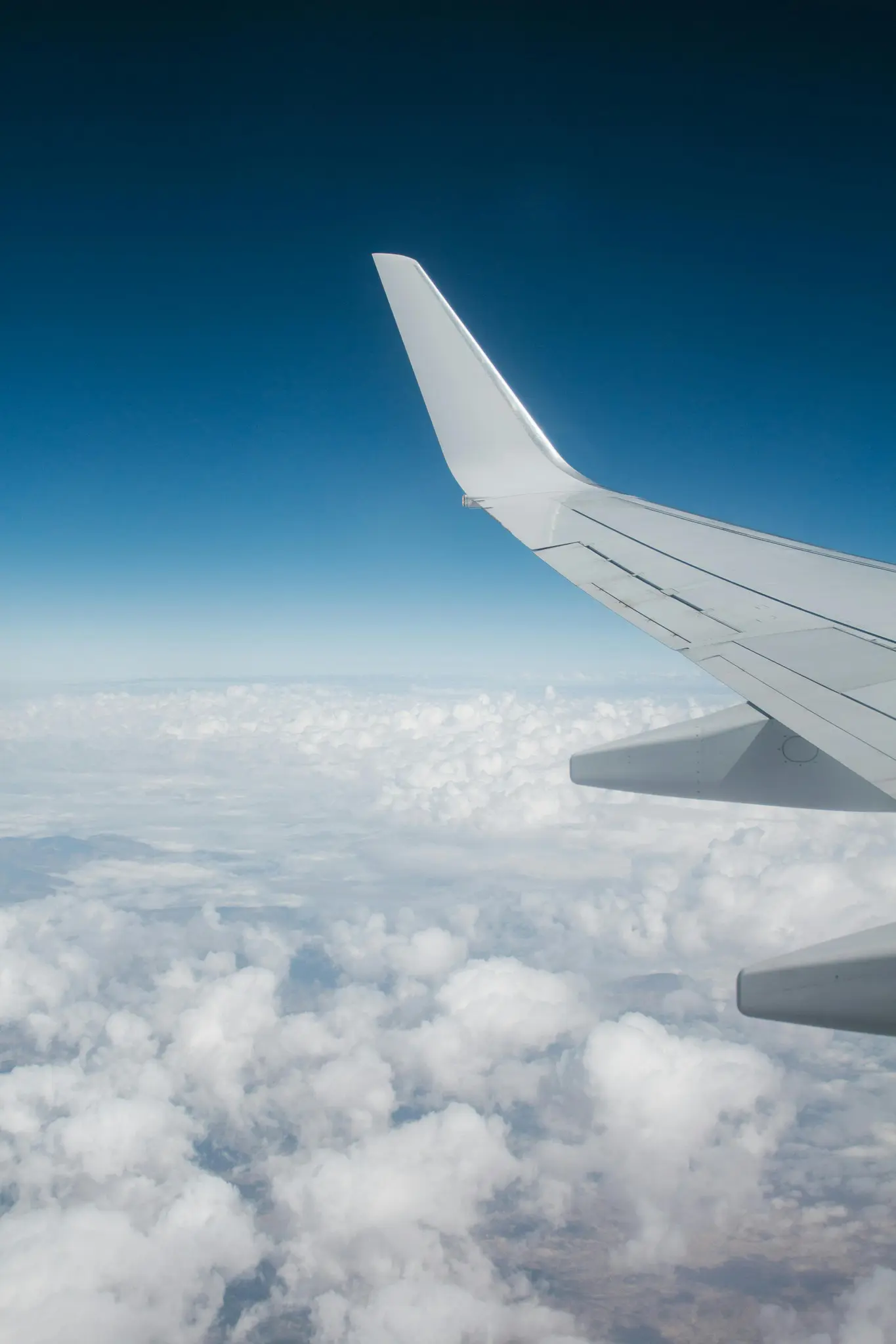 airplane wing over clouds and blue sky