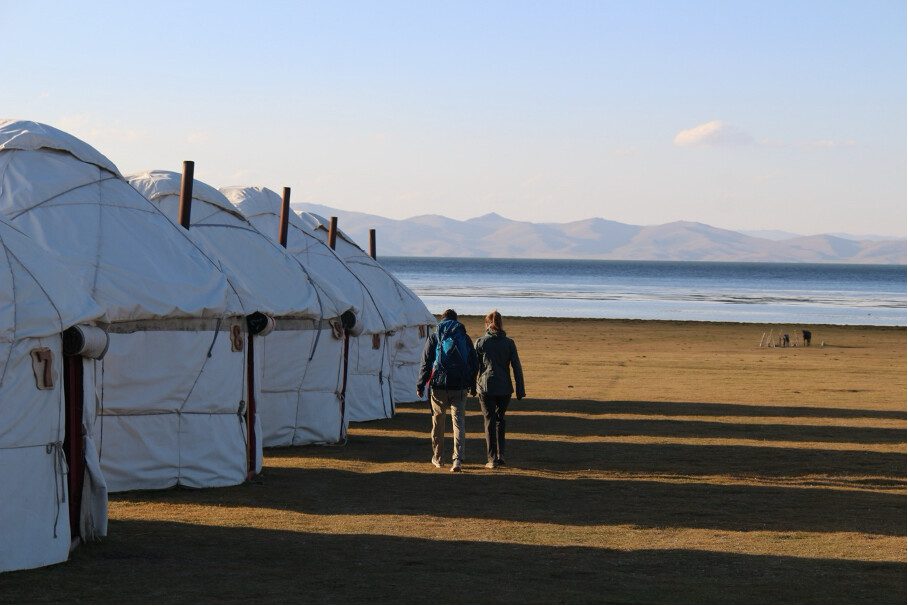 yurt camp along the lake with two people walking